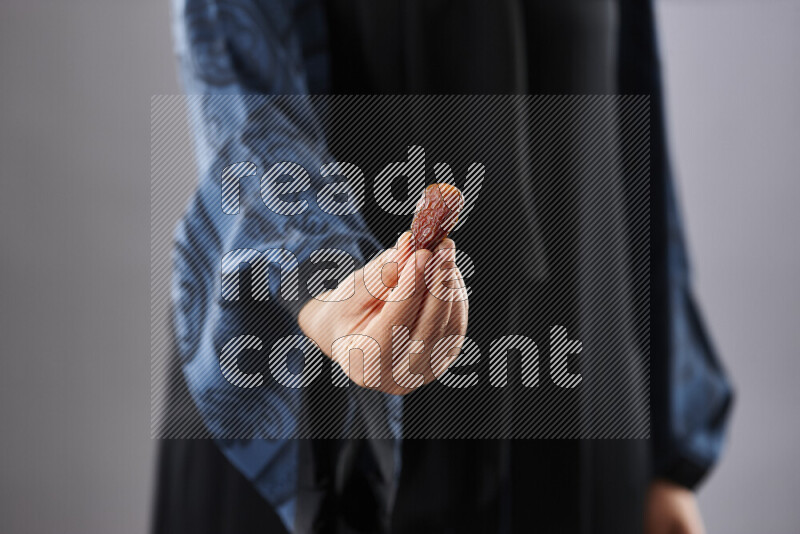 Woman in abaya holding dates in different positions