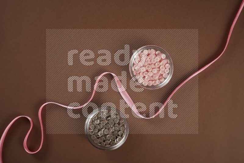 A pink collection of sewing and tailoring tools arranged on a brown background