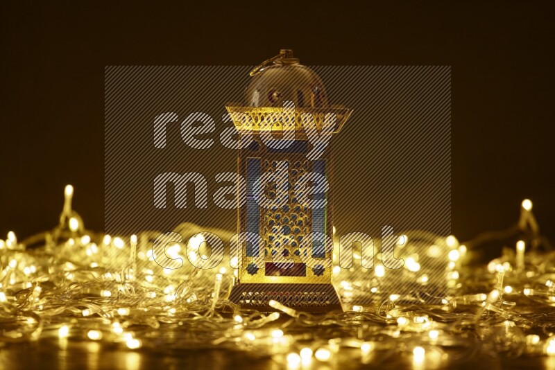 A traditional ramadan lantern surrounded by glowing fairy lights in a dark setup