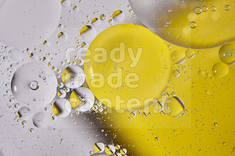 Close-ups of abstract oil bubbles on water surface in shades of white and yellow