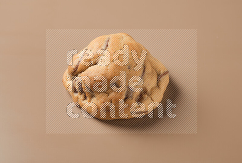 a whole chocolate chip cookie on a brown background