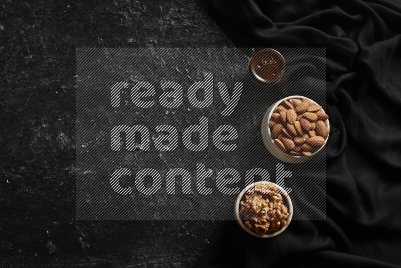 Nuts in pottery bowls with coffee in a dark setup
