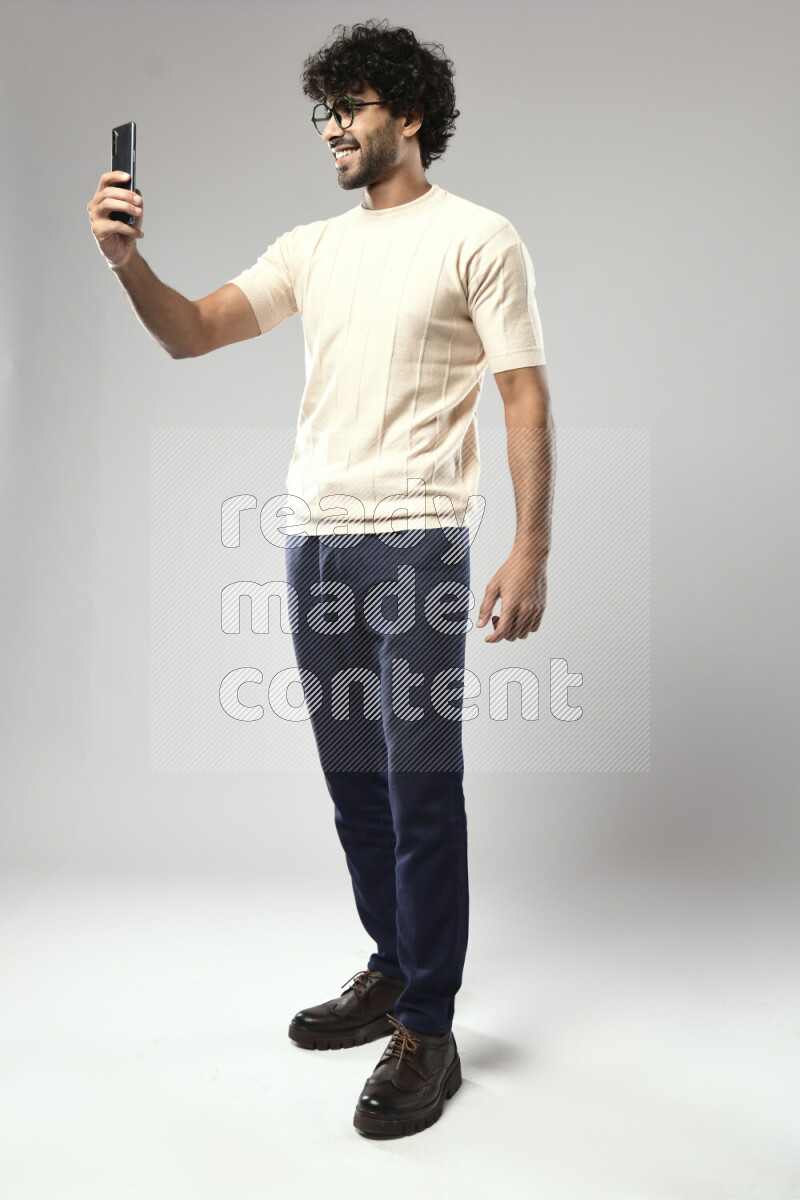 A man wearing casual standing and taking a selfie on white background