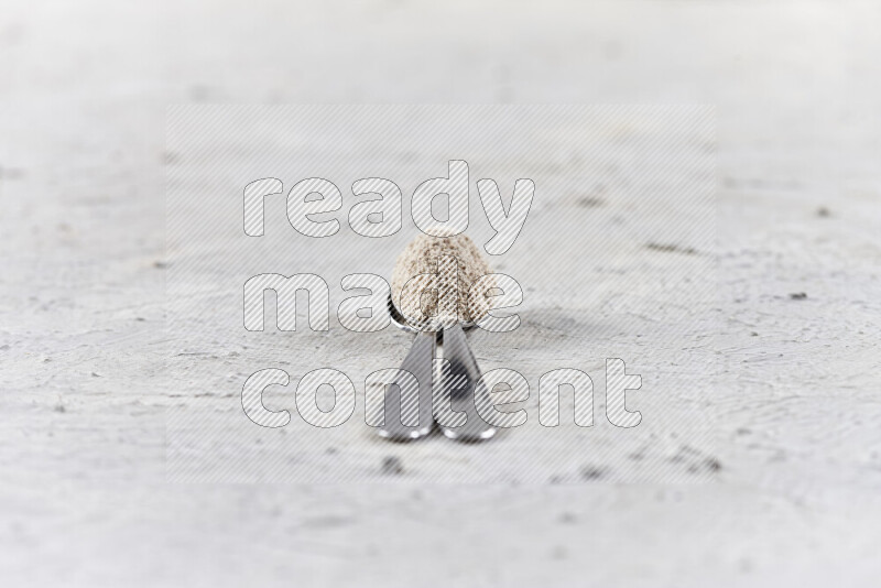 Two metal spoons full of onion powder on white background