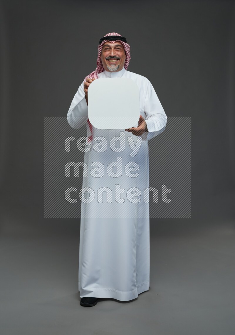 Saudi man with shomag Standing holding social media sing on gray background