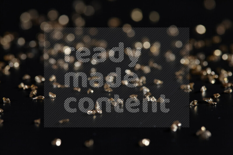 Gold shimmering fragments of glass scattered on a black background