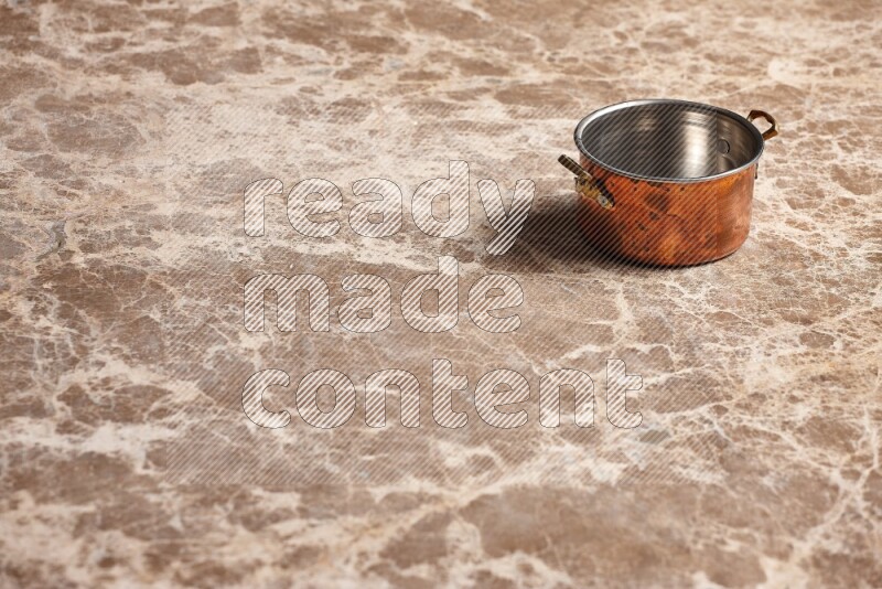 A small copper pot on beige marble background