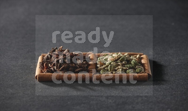 2 squares of cinnamon sticks full of cardamom and star anise on black flooring