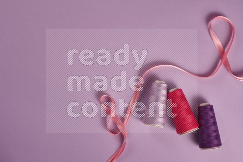 A pink and purple collection of sewing and tailoring tools arranged on a purple background