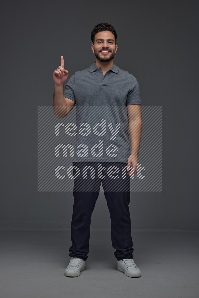 A man wearing casual standing and making multi hand gestures eye level on a gray background