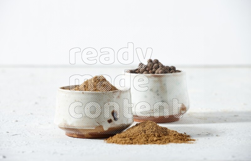 وعاءان بيج، أحدهما ممتلئ ببودرة بهار الفلفل الحلو والآخر بالحبوب مع البودرة والحبوب متناثرة على خلفية بيضاء