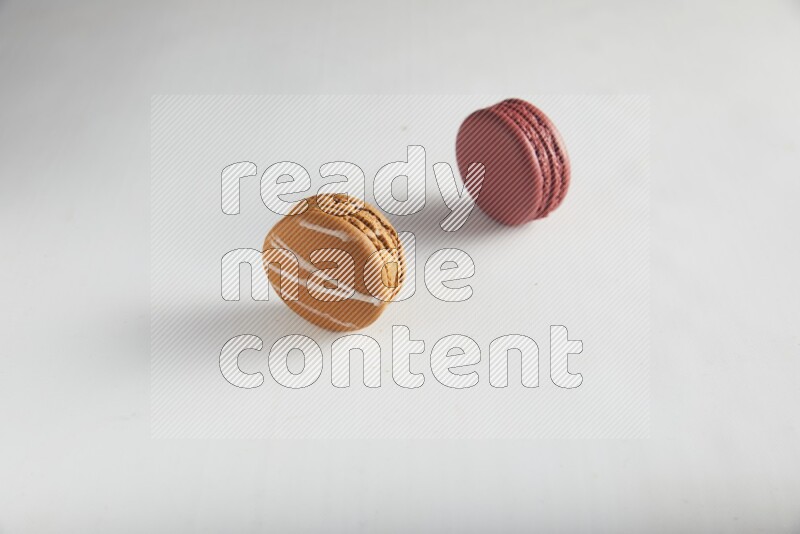 45º Shot of of two assorted Brown Irish Cream, and Red Velvet macarons on white background