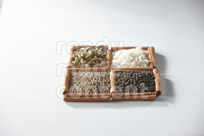 4 squares of cinnamon sticks full of cardamom, salt, white pepper and black pepper on white flooring