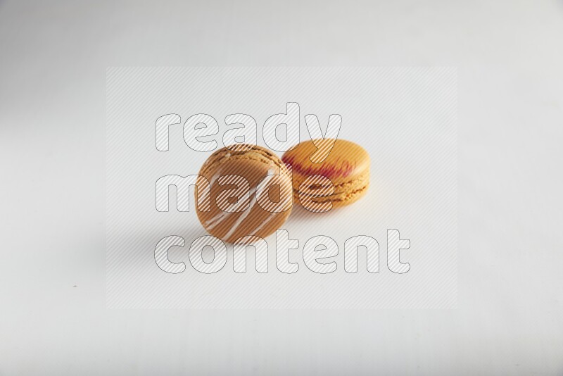 45º Shot of of two assorted Brown Irish Cream, and Orange Exotic macarons on white background