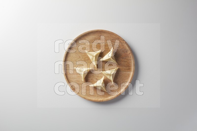 Five Sambosas on a wooden round plate on a white background