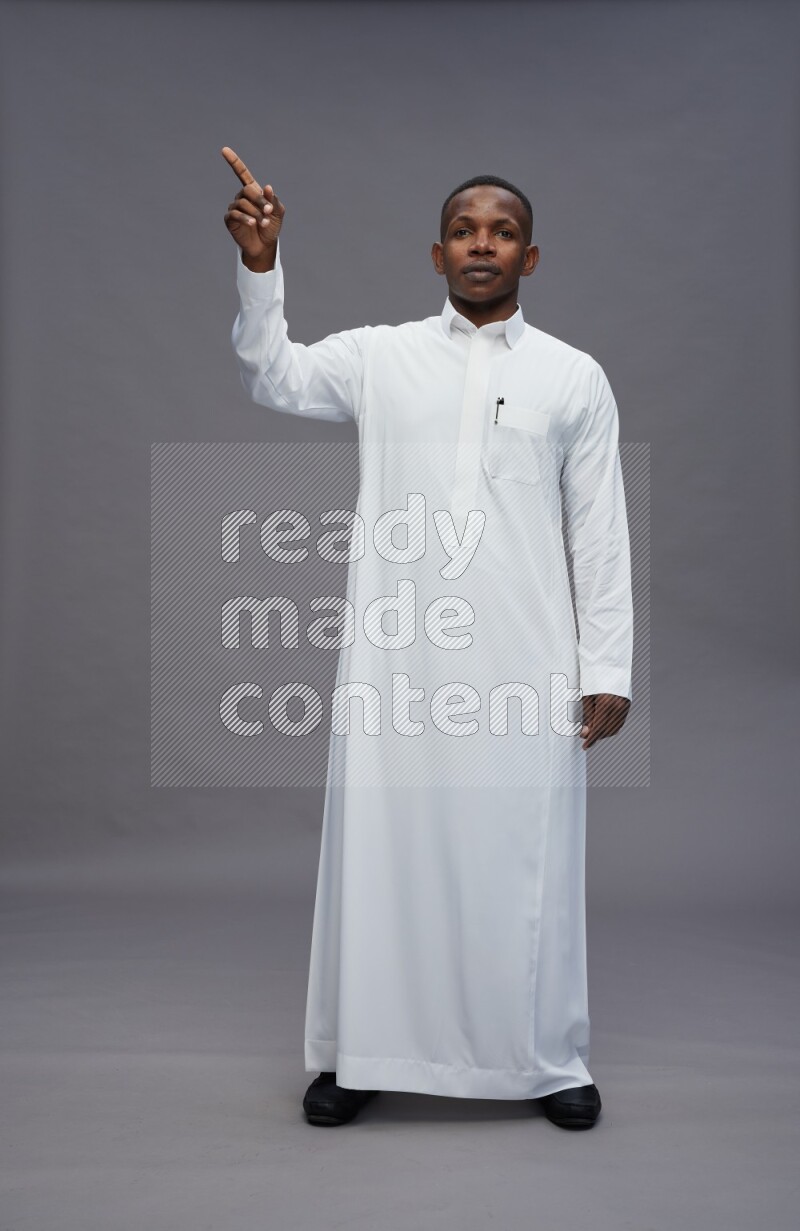 Saudi man wearing thob standing interacting with the camera on gray background