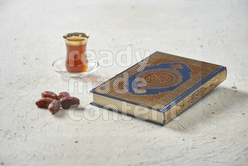 Quran with dates, prayer beads and different drinks all placed on textured white background