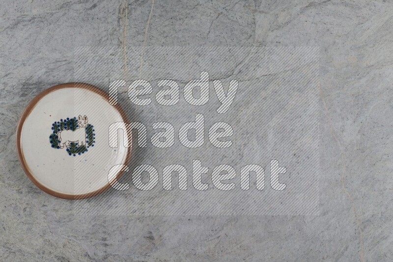 A decorative pottery plate on grey marble background