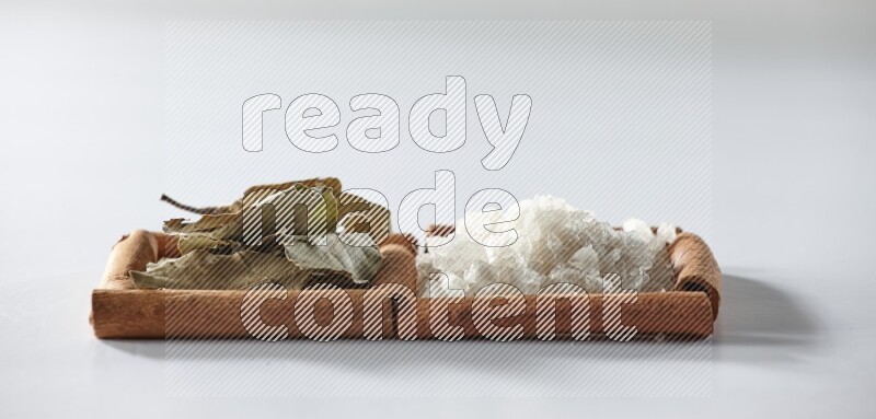 2 squares of cinnamon sticks full of white salt and laurel bay leaves on white flooring