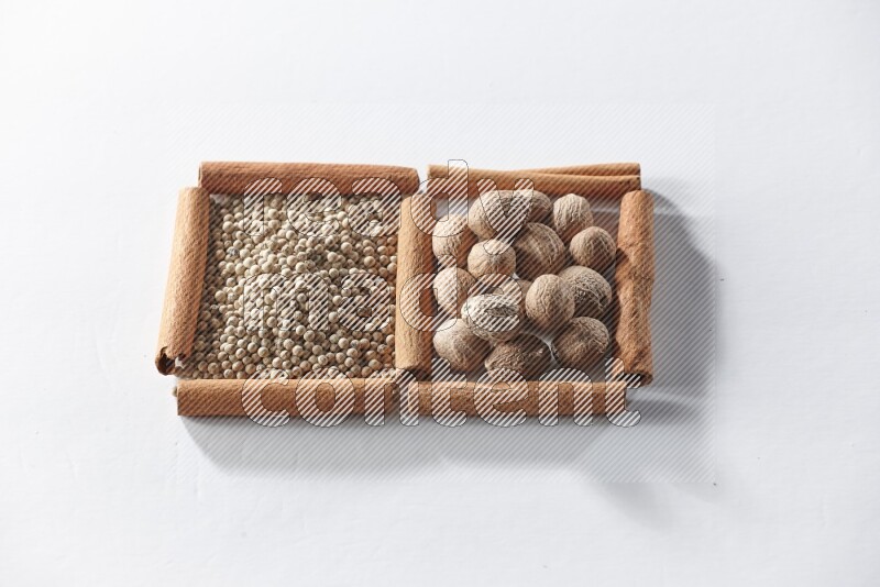 2 squares of cinnamon sticks full of white pepper and nutmegs on white flooring