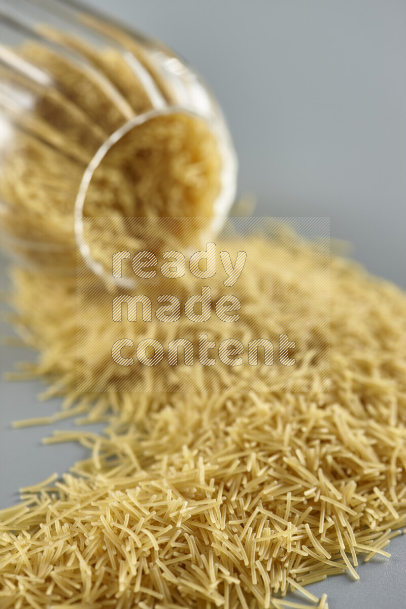 Flipped jar full of raw pasta on light blue background