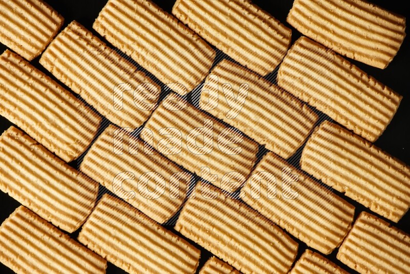 Golden biscuits filling the frame on black background