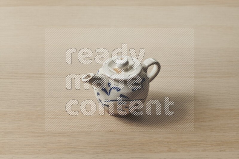 A pottery teapot on light wooden background
