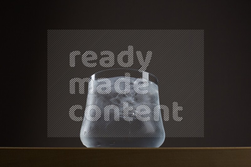 Low angle shot of a glass of water and ice on grey background