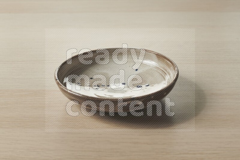 A multicolored pottery plate on light wooden background