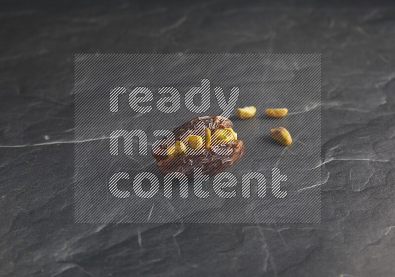 pistachios stuffed madjoul date on a black textured background