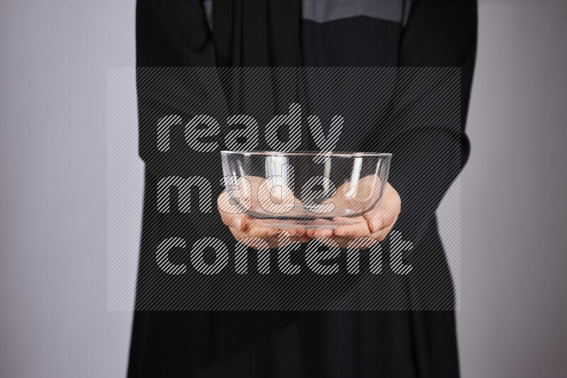 A woman in black abaya holding different glassware in different positions