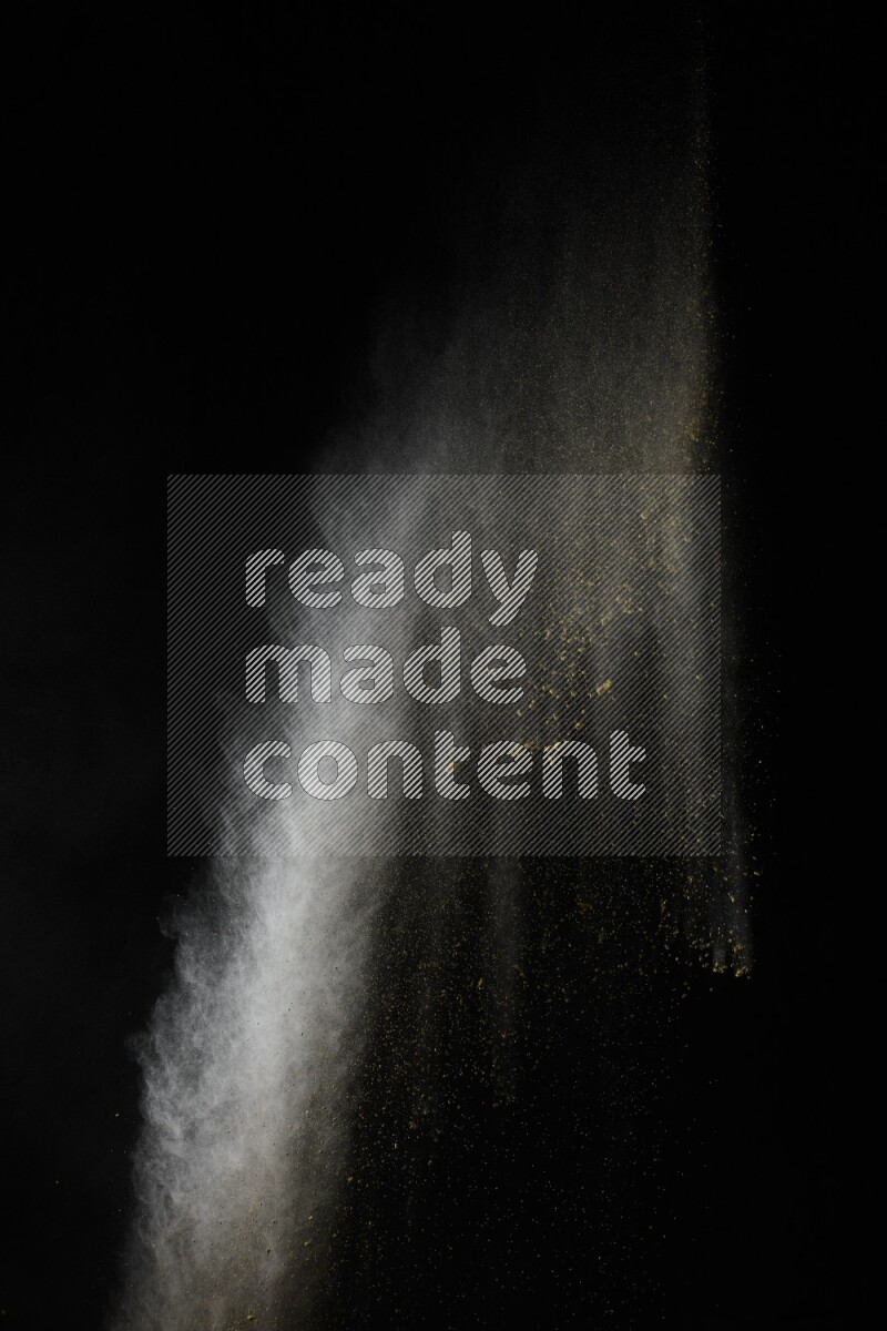 A side view of yellow powder explosion on black background