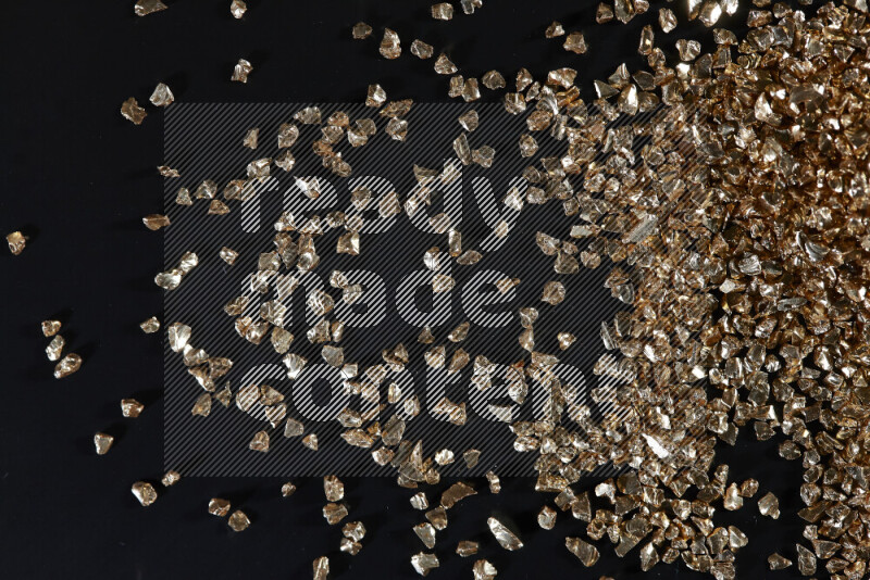 Gold shimmering fragments of glass scattered on a black background