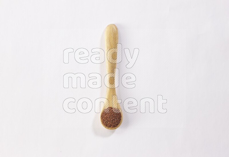 A wooden spoon full of garden cress seeds on a white flooring