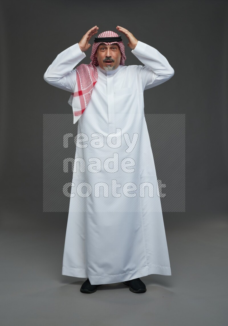 Saudi man with shomag Standing Interacting with the camera on gray background