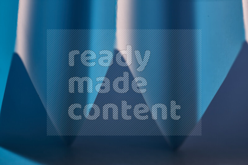 A close-up abstract image showing sharp geometric paper folds in blue gradients