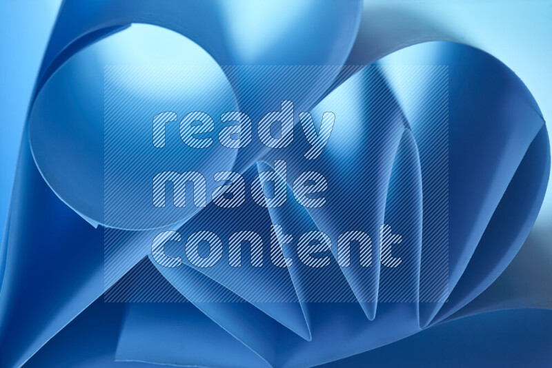 An artistic display of paper folds creating a harmonious blend of geometric shapes, highlighted by soft lighting in blue tones