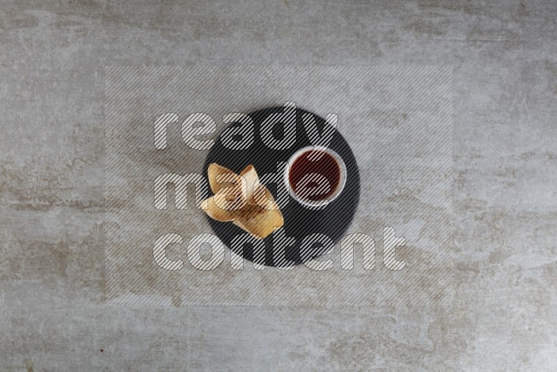 wonton cups with soy sauce ramkin on circle slate on grey textured counter top