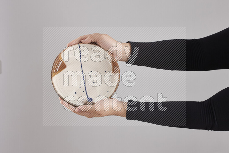 A woman in black abaya holding different pottery essentials in different positions