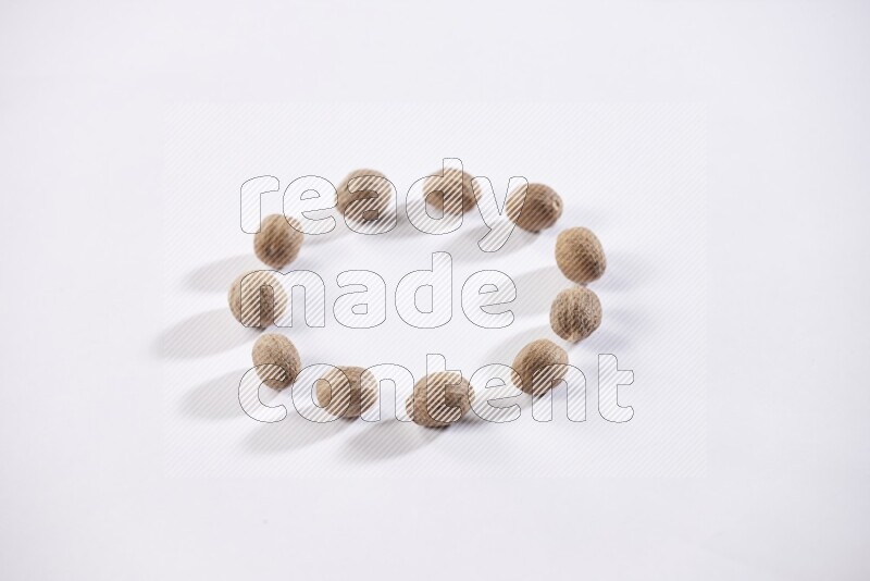Nutmeg seeds in a circle shape on a white flooring