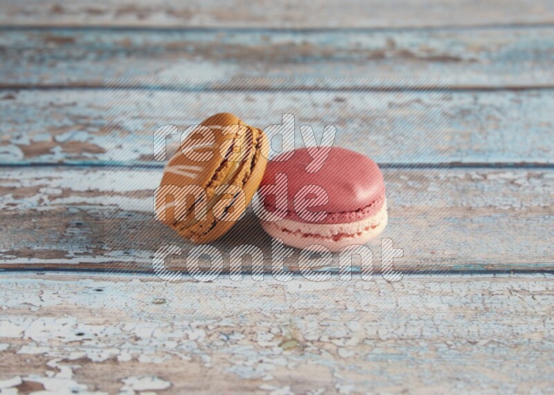 45º Shot of of two assorted Brown Irish Cream, and Pink Litchi Raspberry macarons on light blue background