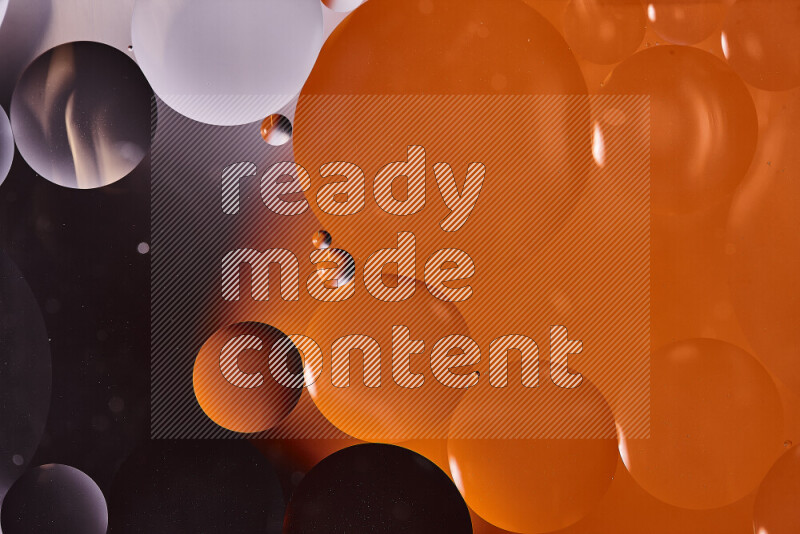 Close-ups of abstract oil bubbles on water surface in shades of black and orange