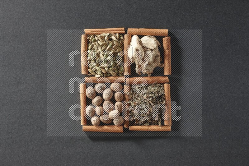 4 squares of cinnamon sticks full of dried basil, cardamom, dried ginger and nutmegs on black flooring