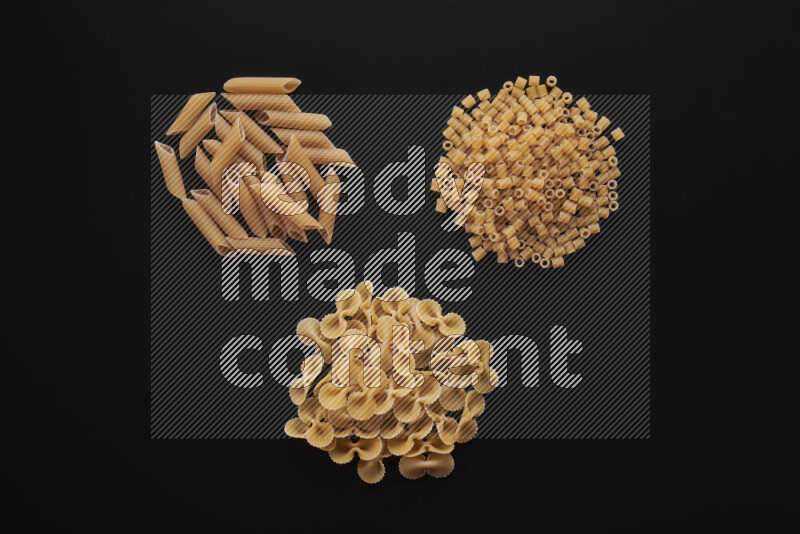 Different pasta types in bunches on black background