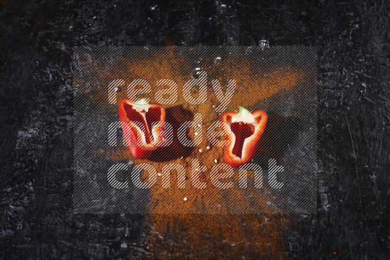 حفنة من بودرة البابريكا مع نصفين من الفلفل الأحمر الحلو على خلفية سوداء