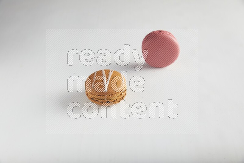 45º Shot of of two assorted Brown Irish Cream, and Pink Raspberry macarons on white background