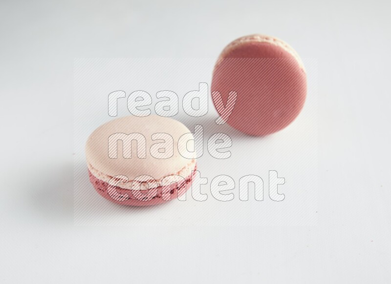 45º Shot of two Pink Litchi Raspberry macarons on white background
