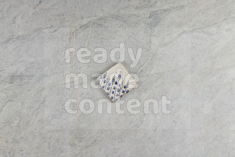 A decorative pottery coaster on grey marble background