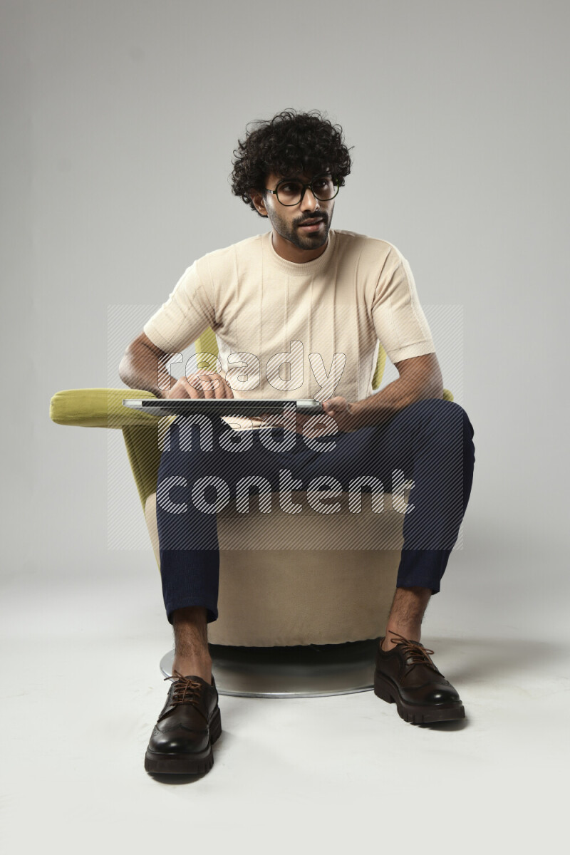 A man wearing casual sitting on a chair holding a laptop on white background