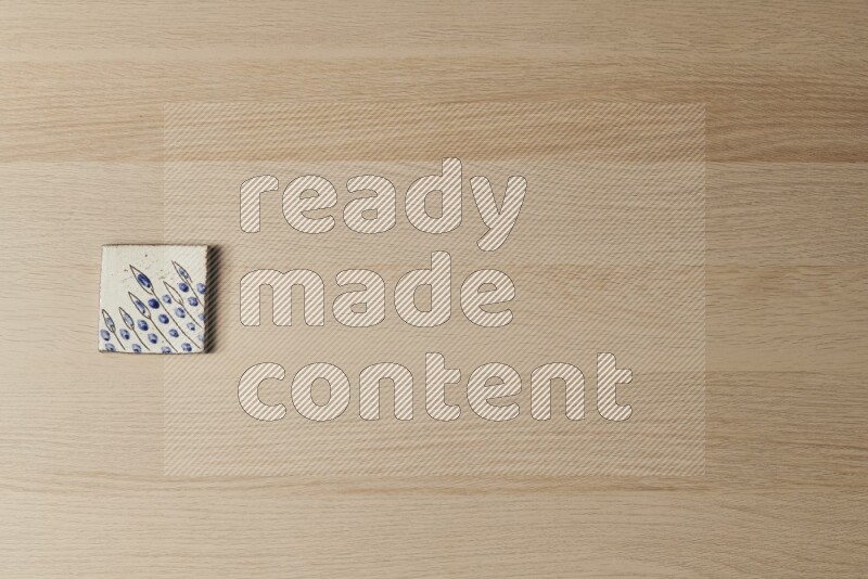 A decorative pottery coaster on light wooden background